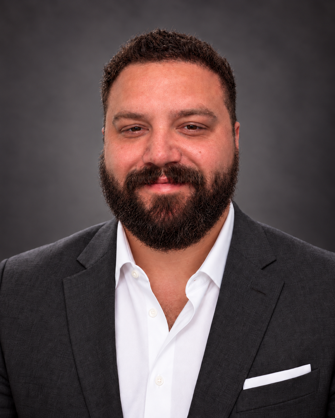 Zachary Butts in a charcoal jacket and white open-collar shirt